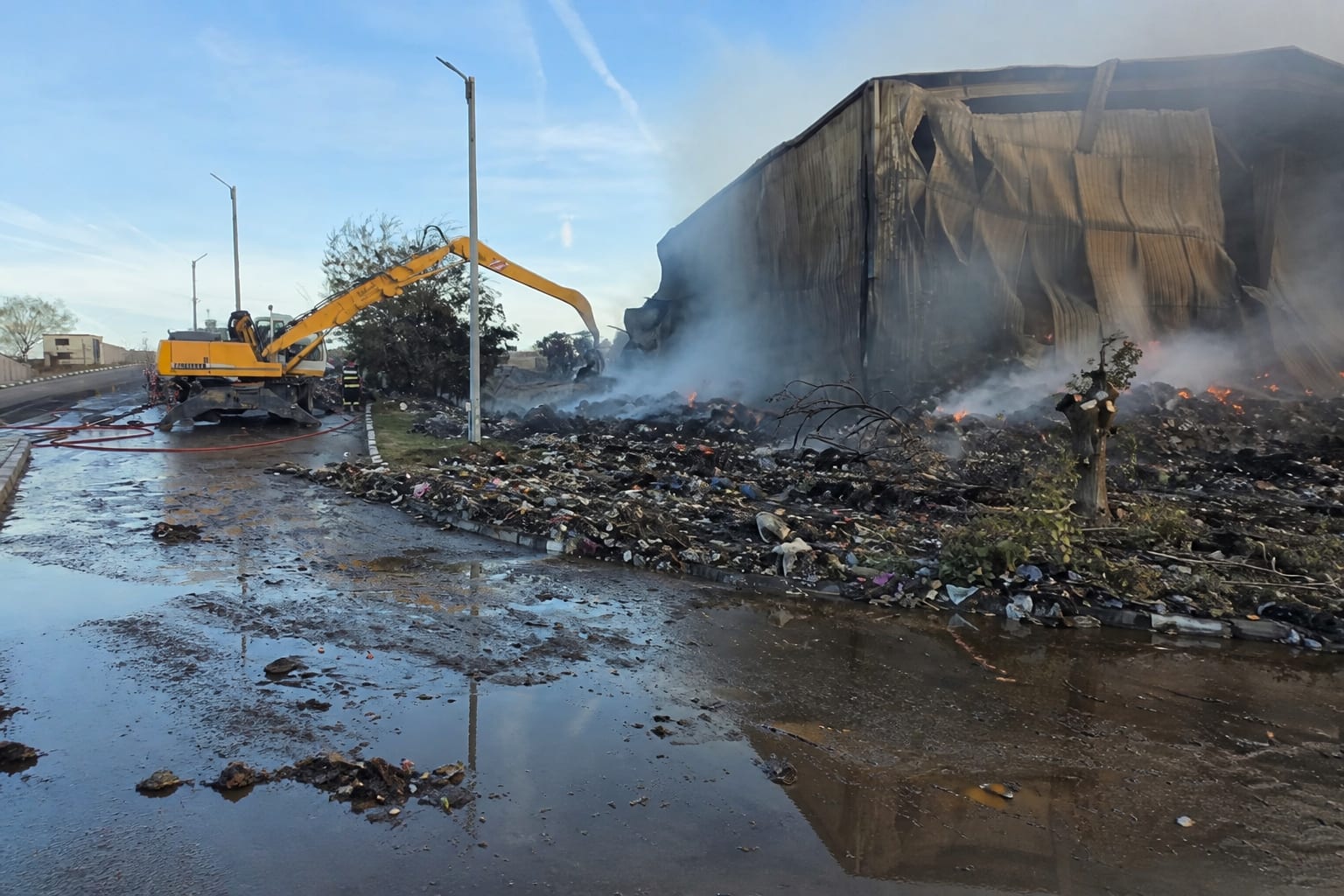 Utilaj intervenind la depozit incendiat