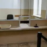 Un ghișeu interior dintr-o instituție publică, prevăzut cu un geam de protecție și un mic orificiu pentru schimbul de documente